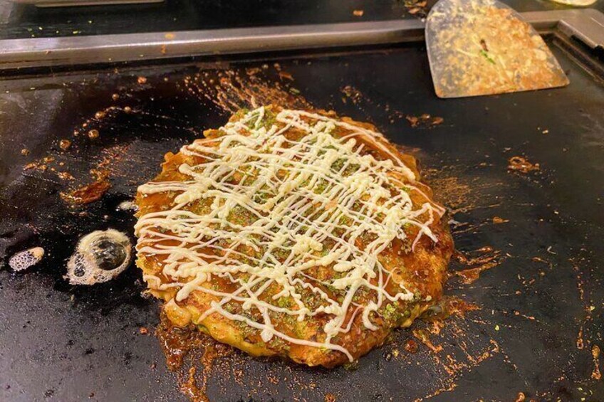 A food item on a hot griddle with a white topping. 3