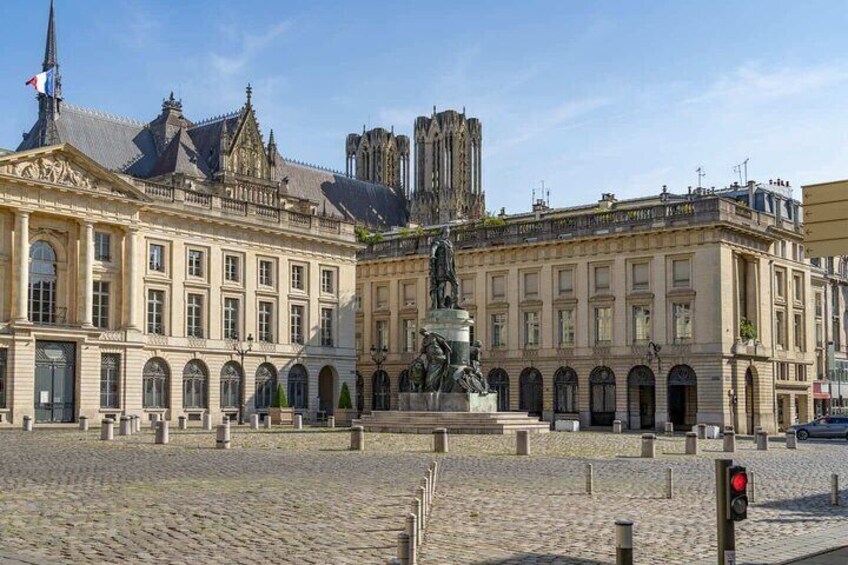 A historic building with a statue in front, cobblestone pavement, and a flag. 3
