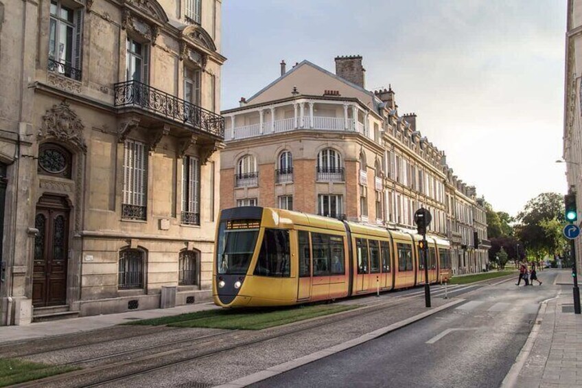 A yellow tram on a city street with historic buildings on either side. 5