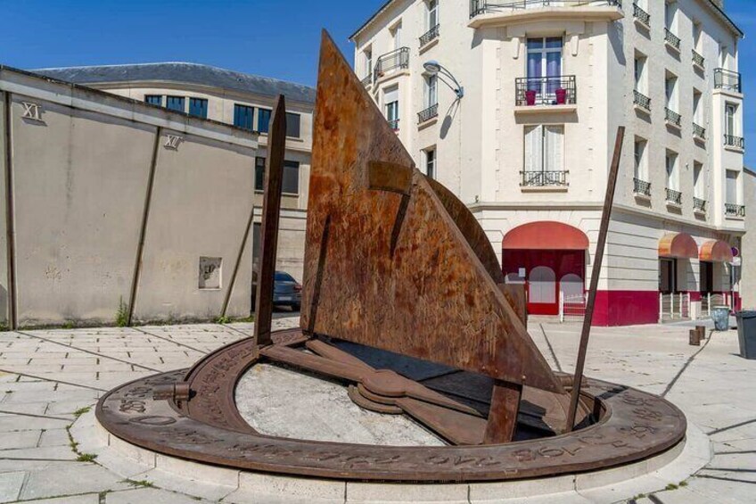 A metal sculpture in a public square with a building in the background. 4