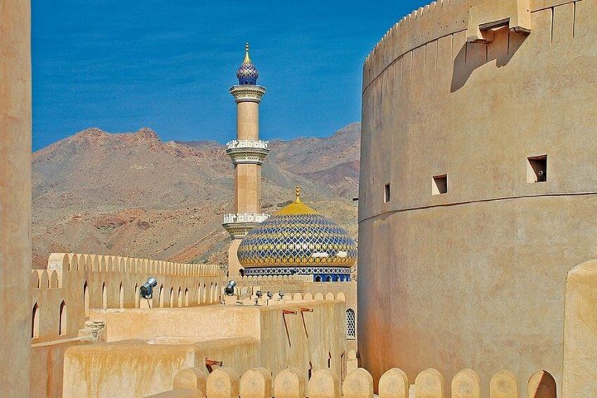 A fortress with a minaret and a dome, surrounded by a wall and desert landscape. 3