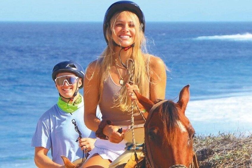 A person riding a horse on a beach with the ocean in the background. 2