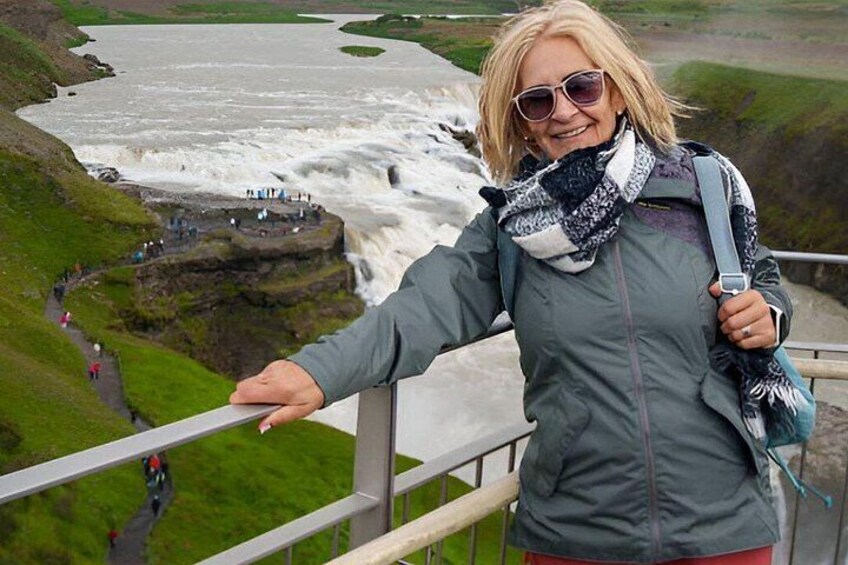A person standing on a railing overlooking a waterfall. 5