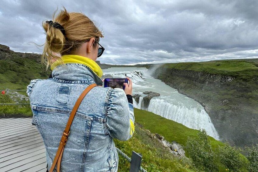A person taking a photo of a waterfall. 2