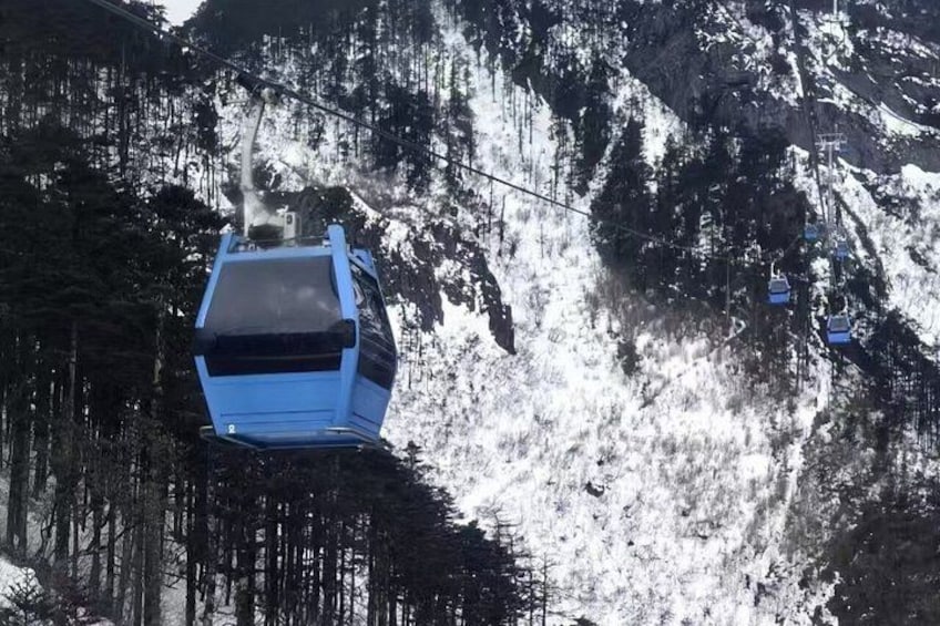 A blue cable car ascending a snowy mountain. 4