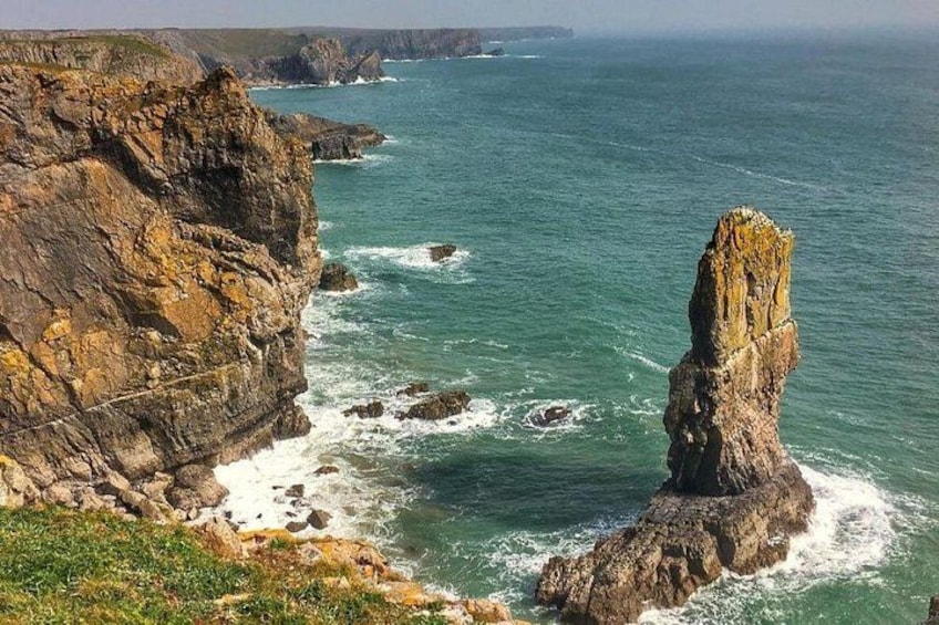 A coastal landscape with a prominent rock formation and cliffs. 5