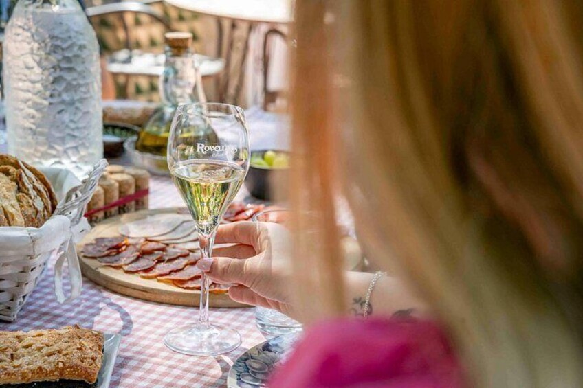 Une table avec un verre de vin blanc, une assiette de charcuterie et une bouteille d’eau. 2