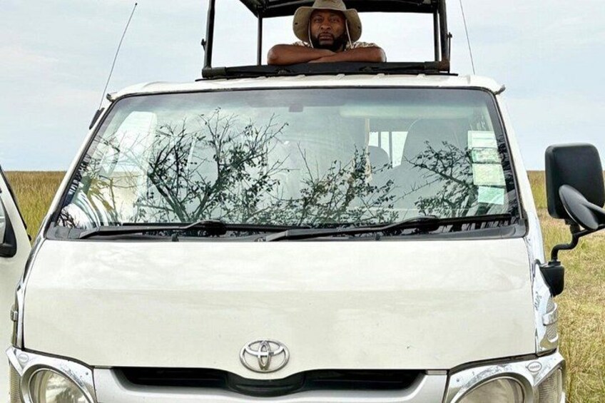 A white Toyota vehicle with a person wearing a hat in the driver's seat. 3