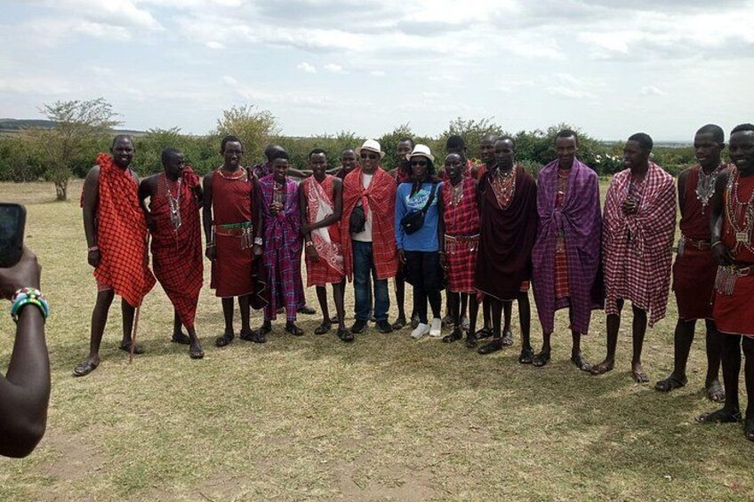A group of people in traditional attire standing in a grassy field. 2