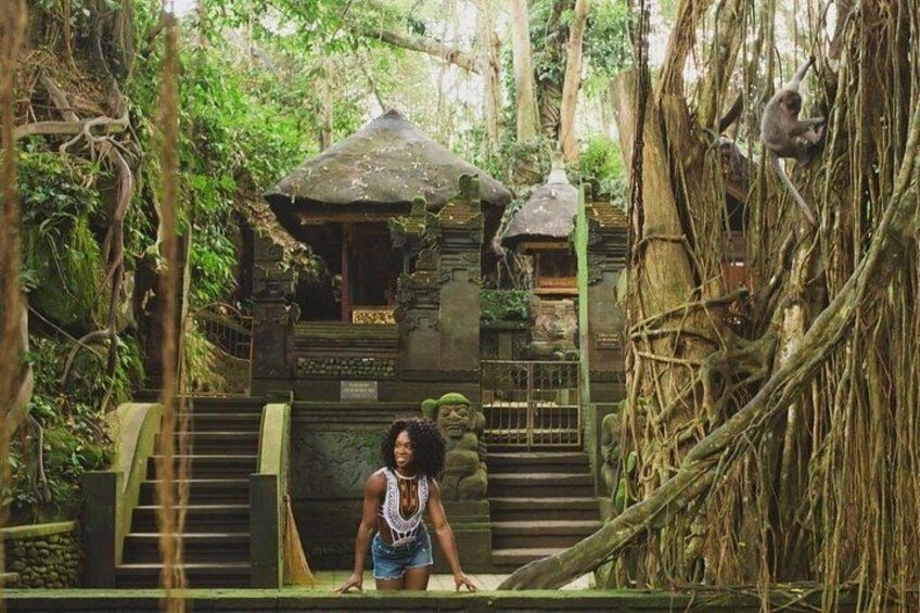 A person standing on a wooden platform with a temple structure in a forested area. 5