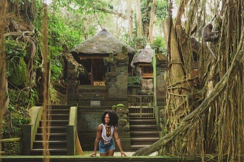 A person standing at the base of a stone staircase leading to a temple surrounded by dense jungle. 5