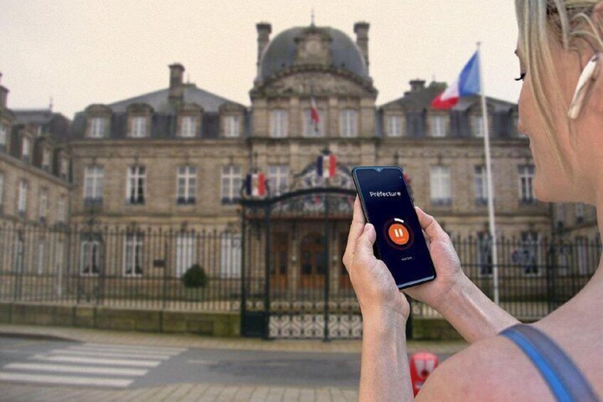 A person holding a smartphone with a map application, standing in front of a historic building with flags. 2