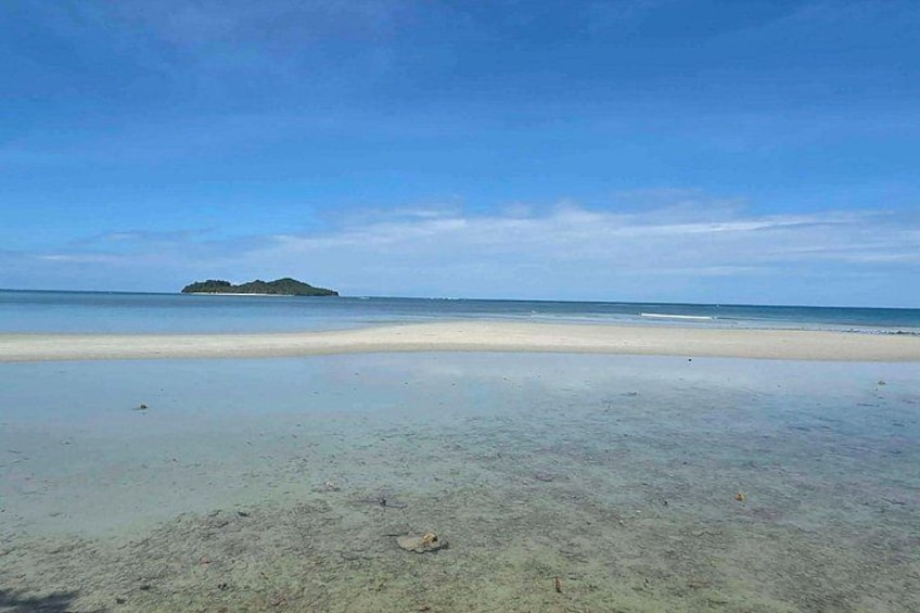 Ein Strand mit klarem Wasser, einem sandigen Ufer und einer kleinen Insel in der Ferne. 2