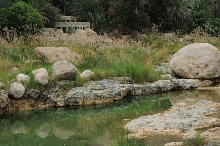 Un ruisseau aux berges rocheuses, parsemé de gros blocs de pierre, avec un petit bâtiment visible au loin. 2