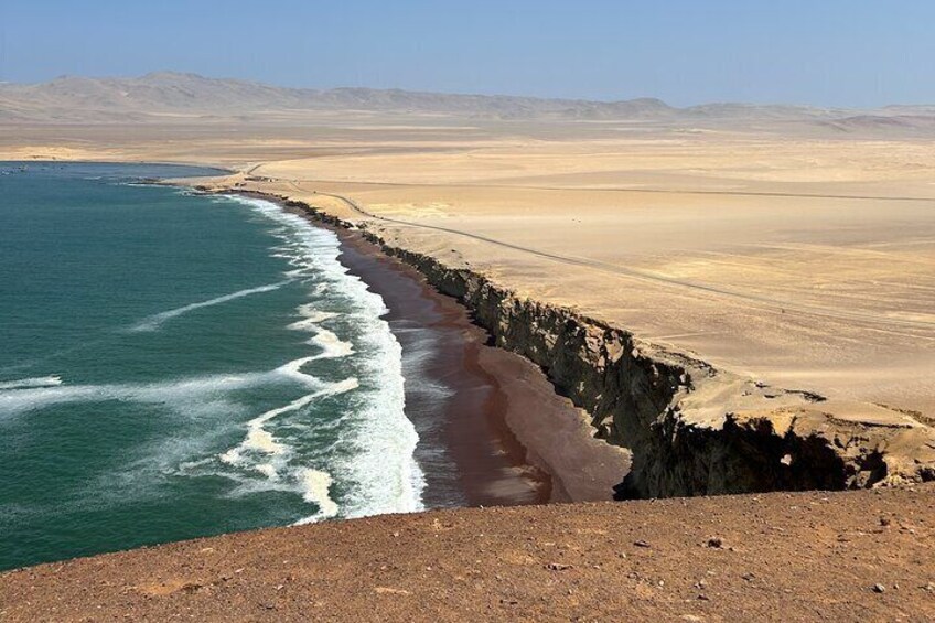 Paesaggio costiero con spiaggia, onde dell'oceano e un deserto sullo sfondo. 2