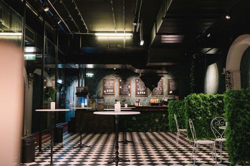 A restaurant interior with a checkered floor, round tables, and a bar area. 2