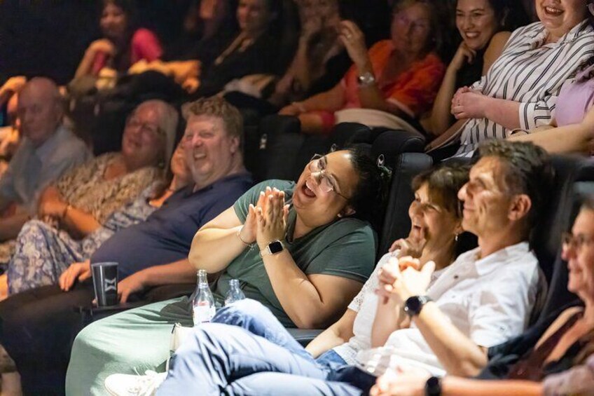 People seated in an auditorium, clapping. 5