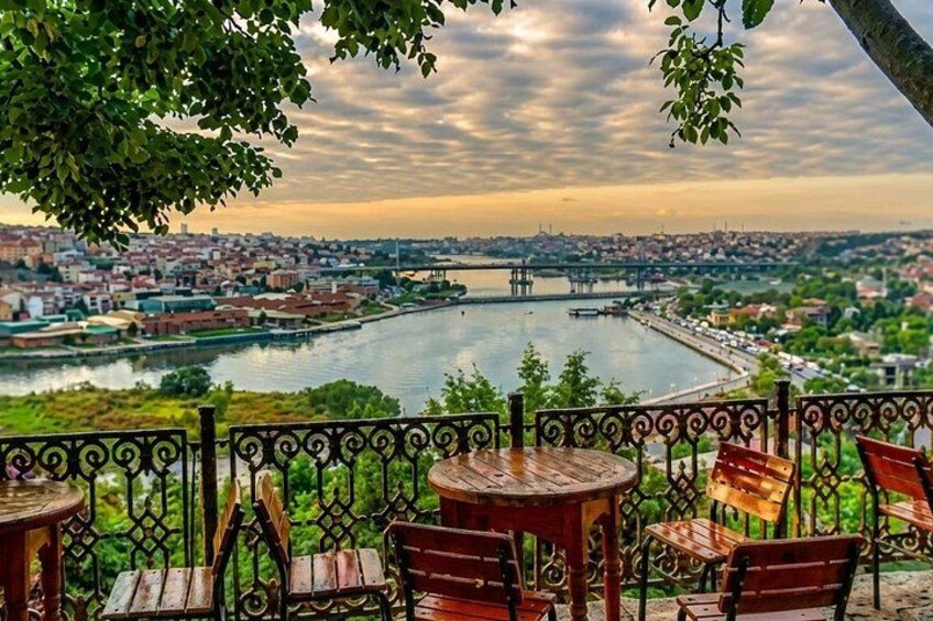 A riverside view with a bridge, a cityscape, and outdoor seating. 1