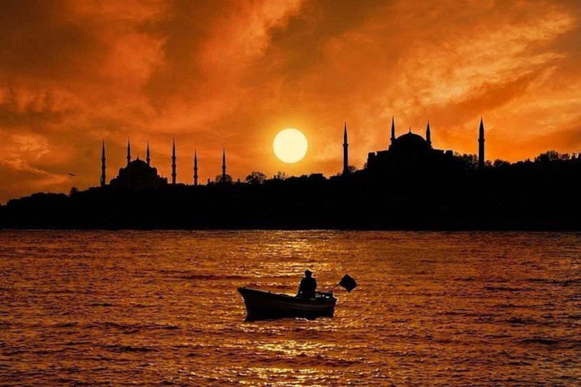 A sunset over a body of water with a silhouette of a mosque and minarets in the background. 2