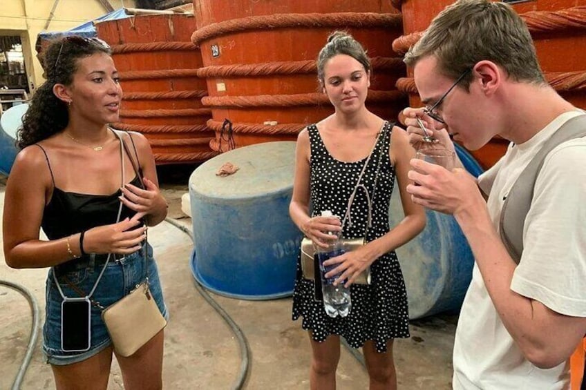 Trois personnes se tiennent à l’extérieur, près de grands conteneurs industriels. 3
