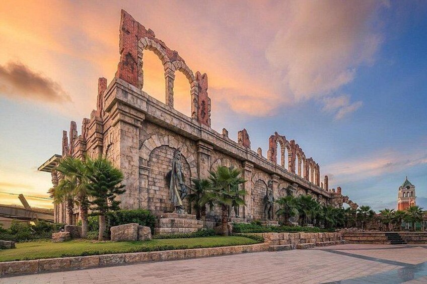 Un edificio histórico de piedra con arcos y estatuas, rodeado de palmeras y un cielo despejado. 4