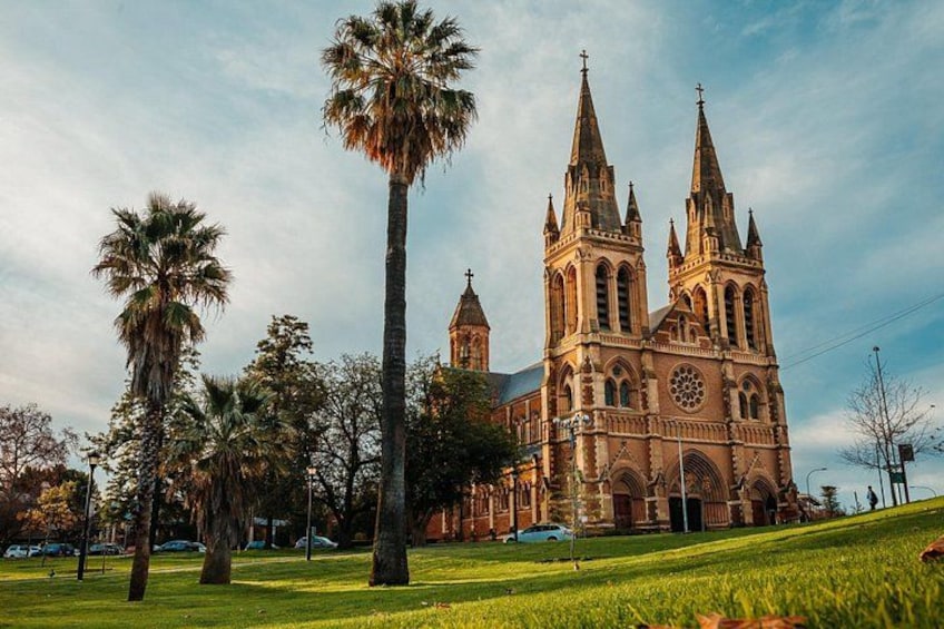A large cathedral with two tall spires, surrounded by palm trees and a grassy area. 4