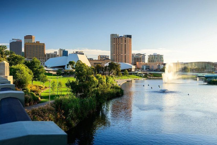 A river with a fountain, a city skyline, and green spaces. 1