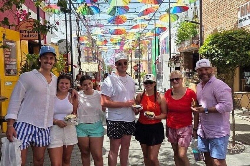 Un grupo de personas caminando por una calle con paraguas de colores arriba. 5