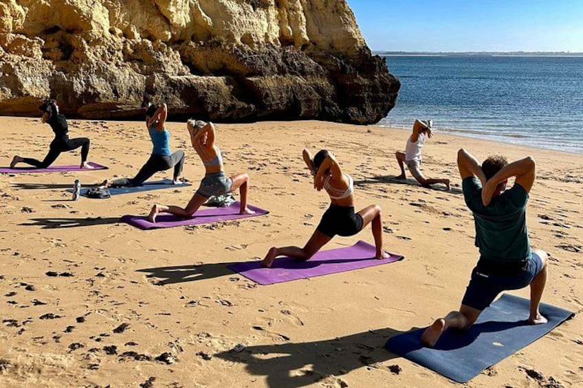 Eine Gruppe von Menschen praktiziert Yoga auf Strandmatten. 1