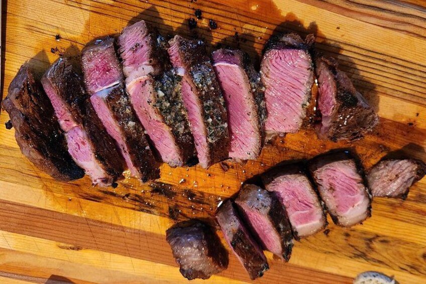 Una tabla de madera con bistec en rodajas. 2