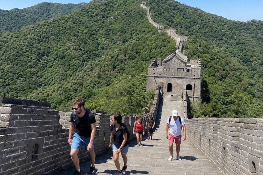 Un grupo de personas caminando por la Gran Muralla China, con montañas verdes y exuberantes al fondo. 1