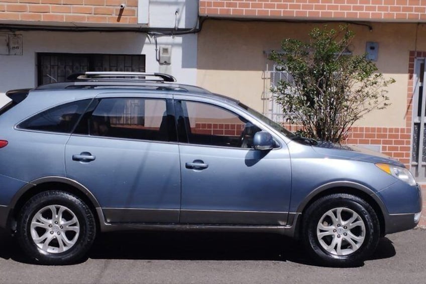 Un SUV argentato parcheggiato di fronte a un edificio in mattoni con un piccolo albero nelle vicinanze. 5