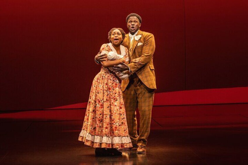Two people on a stage, one in a floral dress and the other in a checkered suit. 3