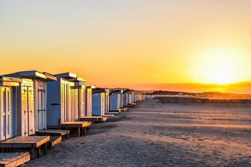 A row of beach huts along a sandy beach at sunset. 3