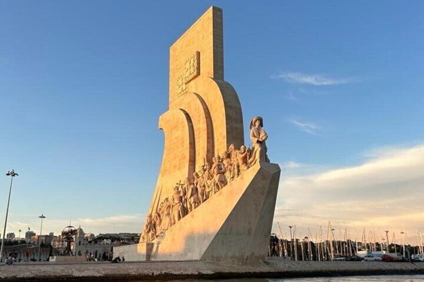 Une grande sculpture abstraite, dont la base est ornée d’un groupe de figures, se dressant sur un ciel dégagé. 1