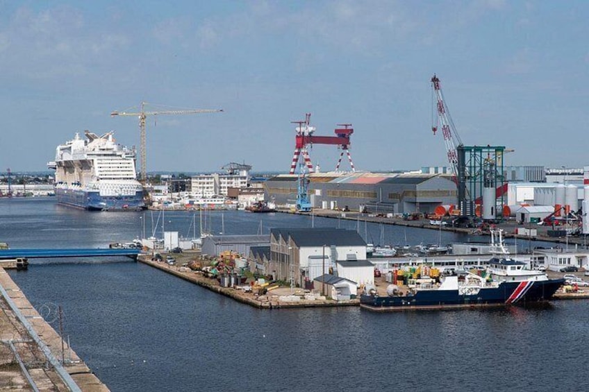 A cruise ship docked at a port with cranes and industrial buildings in the background. 4