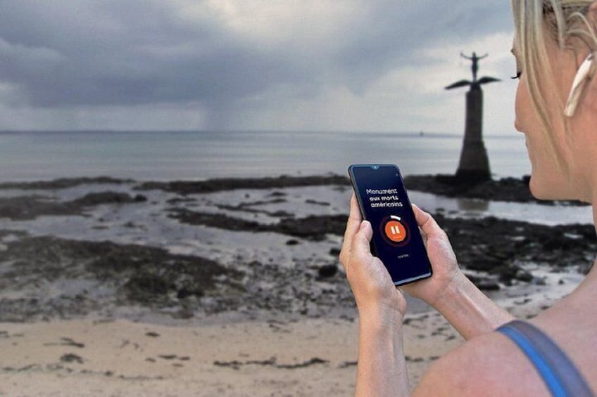 A person holding a smartphone with a beach and a lighthouse in the background. 5