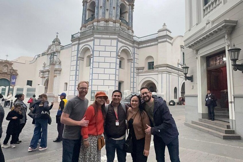 Un gruppo di persone che posa davanti a un edificio storico con un campanile. 2