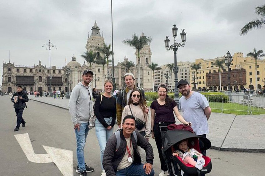 Un gruppo di persone in piedi su un marciapiede, con un edificio storico sullo sfondo. 3