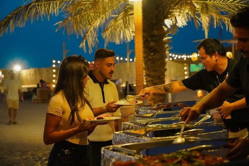 People dining outdoors at night with palm trees and string lights in the background. 5