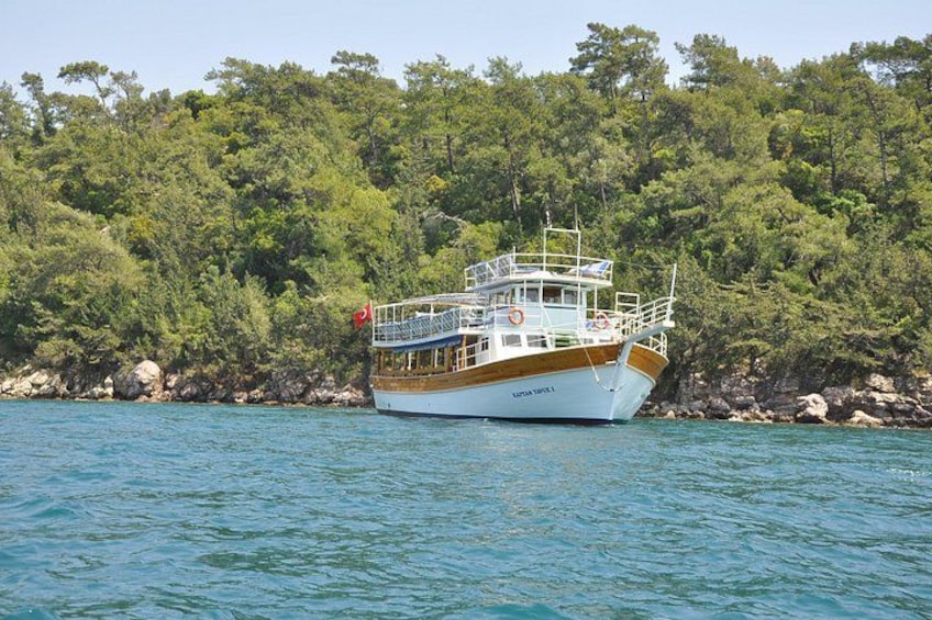 A boat on calm water with a forested shoreline in the background. 2