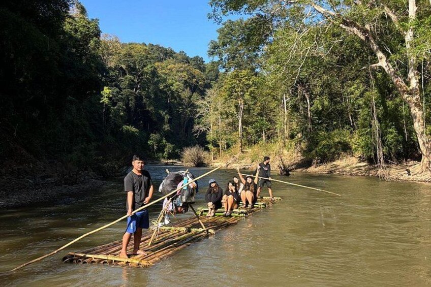 People on a bamboo raft in a river surrounded by trees. 1
