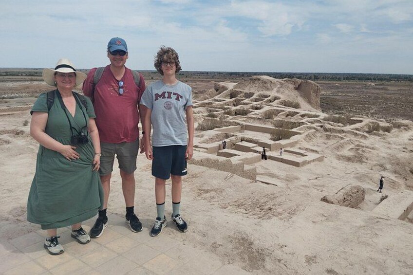Una familia de pie frente a un sitio arqueológico con ruinas antiguas. 1