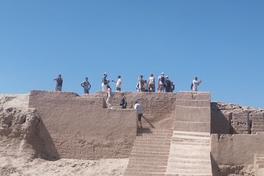 A group of people standing on a stepped structure with a clear blue sky in the background. 2