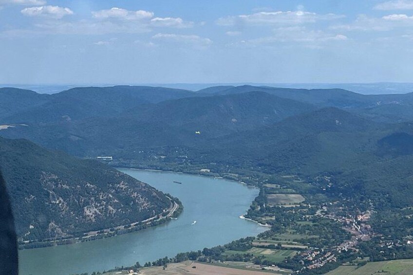Une rivière serpente à travers un paysage montagneux, avec une petite ville et des bâtiments qui bordent ses rives. 3