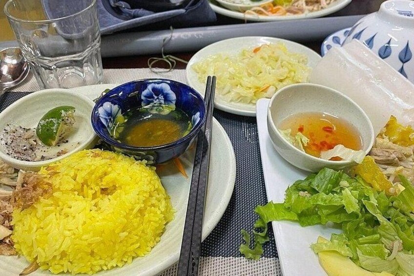 A table with various dishes including yellow rice, a bowl of soup, and a plate of vegetables. 3