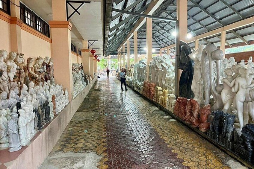 A covered walkway with rows of statues and sculptures. 5