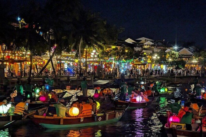 A nighttime riverside scene with boats and illuminated buildings. 4