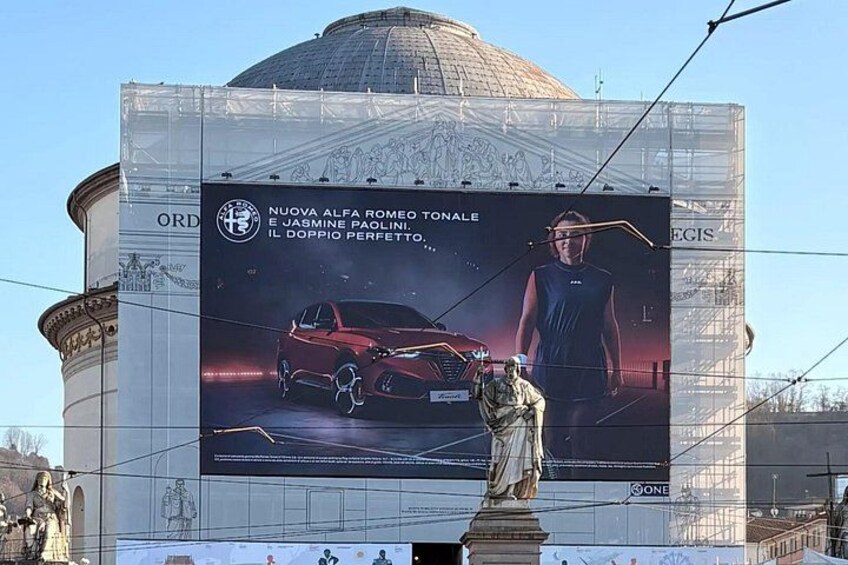 Eine Werbetafel mit einem Auto und einer Statue. 2