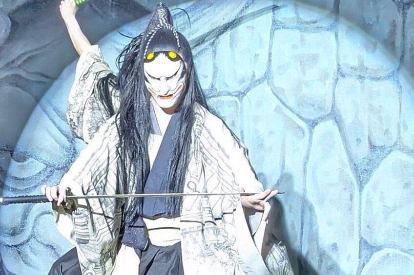 A person in traditional attire holding a sword, with a stone wall in the background. 3
